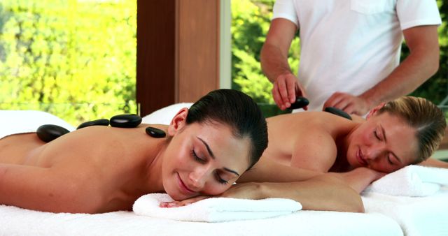 Relaxed friends enjoying hot stone massages at a luxury spa