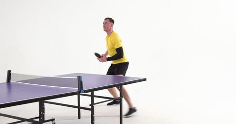 Male Athlete Practicing Table Tennis in Studio with Paddle