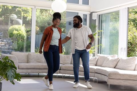 African american couple dancing in bright modern living room wearing white sneakers