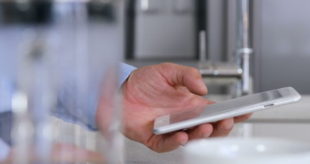 Man Holding Smartphone in Modern Kitchen using Technology - Download Free Stock Images Pikwizard.com