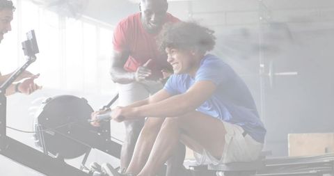 Indoor rowing intensity: athlete pushing ergometer while coach filming on smartphone gimbal