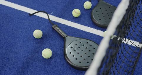 Padel tennis rackets and balls on blue court