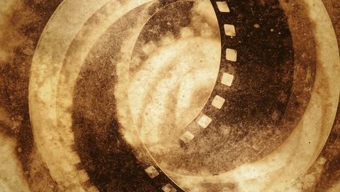 Spiraling sepia filmstrip showing grunge sprocket holes and concentric circular texture
