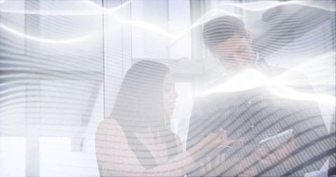Business team collaborating on tablet by office window with blinds glare and reflections