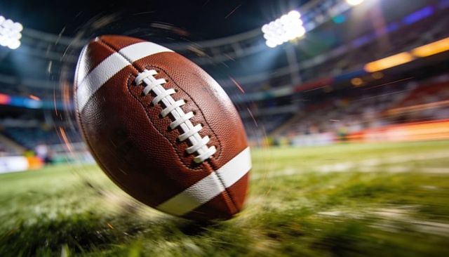 Spinning american football skimming turf under stadium floodlights night motion blur