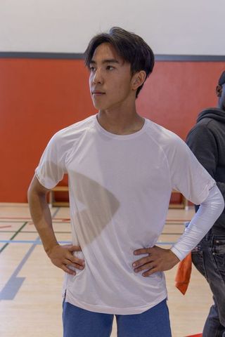 Asian male athlete standing in gym wearing white compression sleeve and training shorts