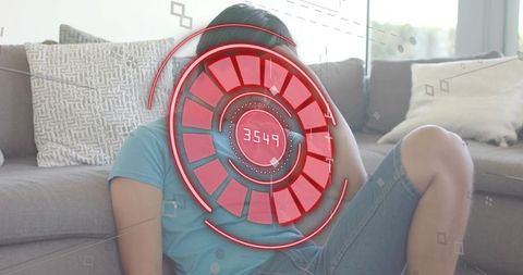 Relaxing asian man reclining on sofa touching head with red futuristic hud interface overlay