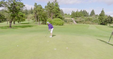 Senior women golfers putting on lush green course