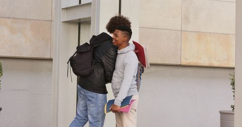 Campus friends embracing at entrance, diverse students with backpacks and folders