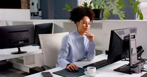 Focused businesswoman typing on office computer in modern workspace
