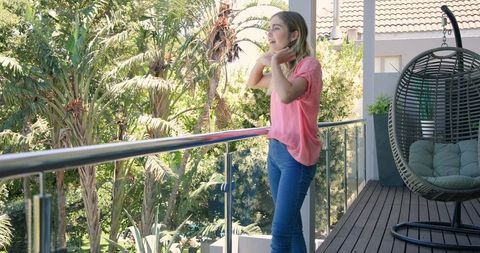 Woman Relaxing on Sunny Balcony Surrounded by Greenery and Serenity