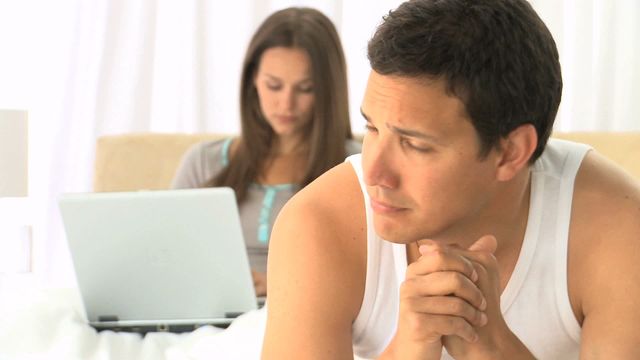 Video depicts a sad man thinking deeply while his spouse concentrates on working with a laptop on the bed. Ideal for illustrating themes in relationships, emotional moments, work-life balance, mental health, and modern lifestyle challenges. Useful for blog posts, articles, or social media content about personal reflection, relationship dynamics, and emotional well-being.