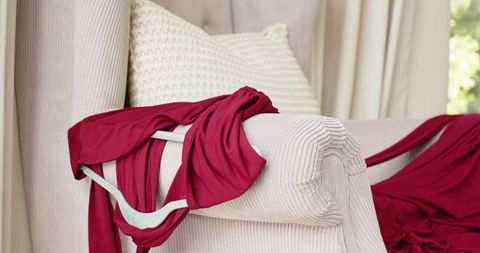 Magenta dress draping over beige ribbed armchair with teal strap and cream cushion