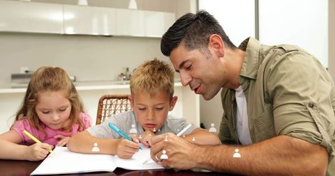 Father guiding children with homework at kitchen table sharing focus and support parenting