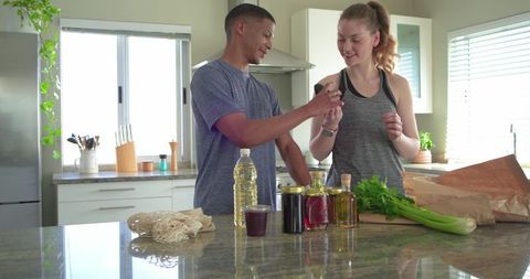 Couple unpacking groceries choosing olive oil and preparing healthy meal in bright kitchen