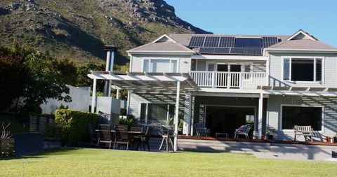 Modern two-story coastal home featuring solar panels and pergola on manicured lawn