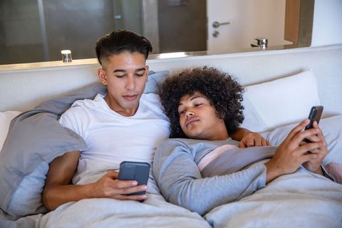 Couple Relaxing Together in Bed Sharing Smartphone Moments