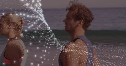 Couple jogging on beach with digital particle ribbon illustrating motion and fitness