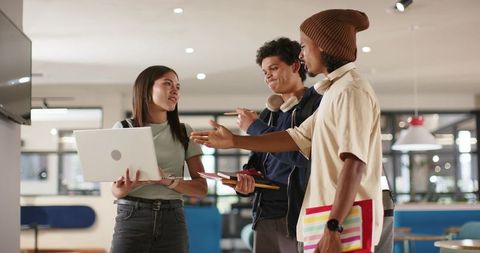 Diverse professionals collaborating with laptop and notebooks in modern coworking space