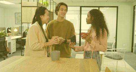Diverse coworkers chatting and collaborating over coffee in office break area