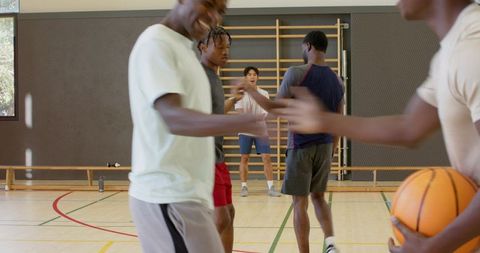 Coach signaling drill with african american players practicing basketball teamwork in gym