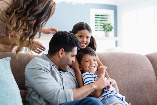 Family enjoying quality time together in a cozy living room. Perfect for illustrating family bonding, home life, and joyful moments. Ideal for use in advertisements, family-oriented blogs, and lifestyle articles.