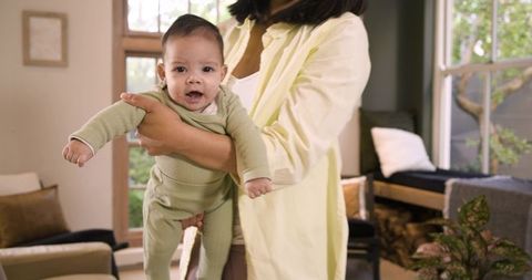 Mother Holding Infant Inside Cozy Living Room Creating Nurturing Ambiance