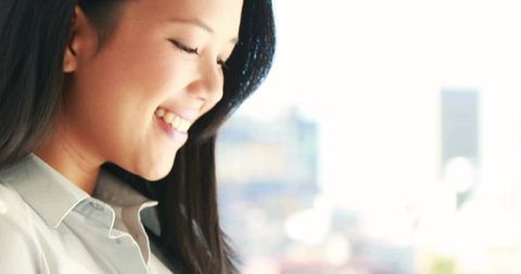 Asian Businesswoman Smiling Against Urban Skyline