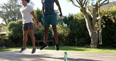 Diverse friends jumping energetically on backyard deck