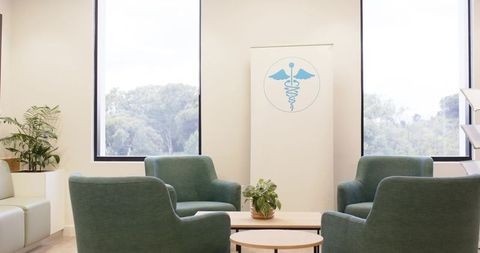 Calm modern clinic lobby featuring green seating, biophilic plants and medical banner