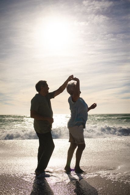 Full length side view of senior couple enjoying dance on shore at beach against sky. lifestyle, love and weekend.