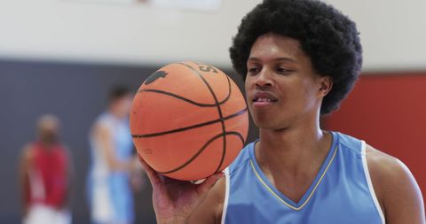 Basketball player balancing brown ball on indoor court