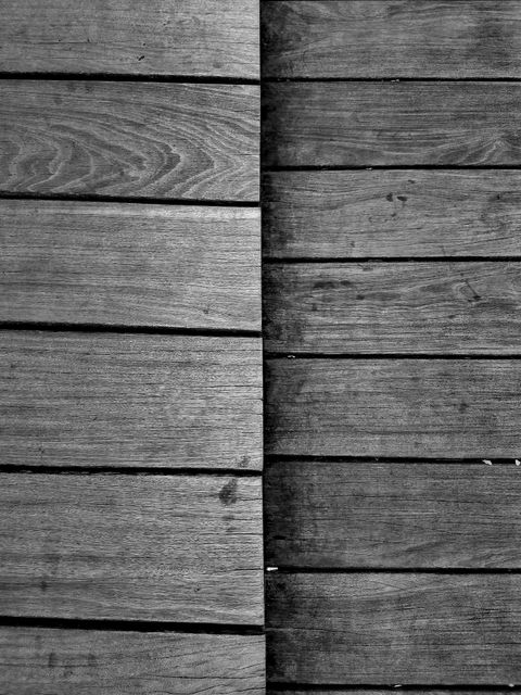 Two halves of wooden planks placed next to each other in contrasting shades, offering a visual comparison. The distinct grain and texture of the planks add a rustic and natural touch. Ideal for use in design inspiration boards, backgrounds for nature-related topics, or themes focusing on contrast and symmetry in materials.