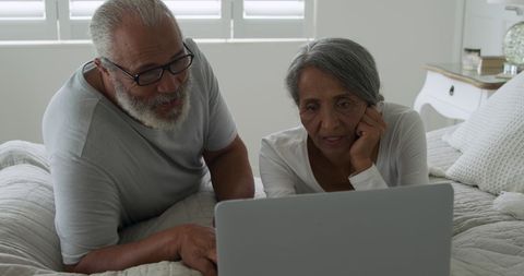 Elderly couple browsing laptop in comfort of home