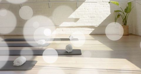 Sunlit minimalist yoga studio lining dark gray mats with rolled white towels