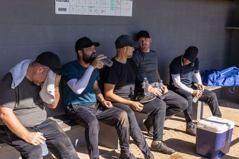 Baseball team resting in dugout hydrating between innings under bright sun