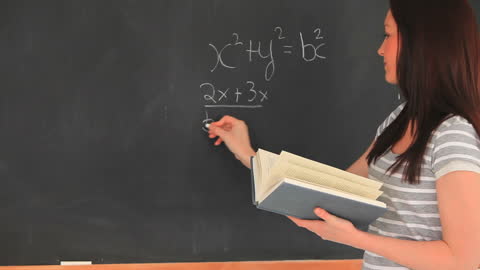 Young Woman Writing Mathematics on Blackboard in Classroom Setting