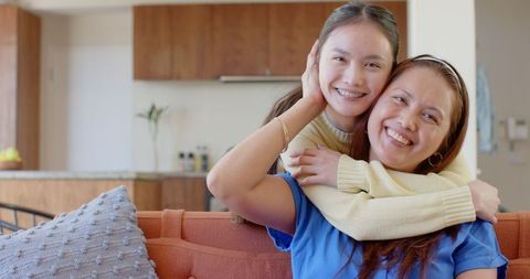 Smiling mother and daughter embracing in cozy home