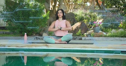 Practicing mindful yoga by pool with wearable tech, meditation reflection in backyard garden