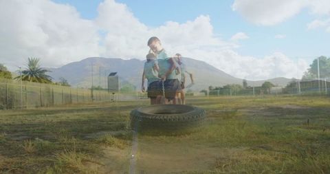 Boy overcoming physical challenge on field with tire