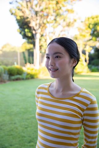 Smiling woman enjoying sunny garden wearing striped shirt