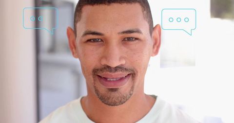 Close-up smiling man in bright interior with chat bubble overlays for messaging concept