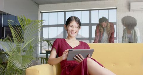 Smiling Asian Businesswoman Using Tablet in Modern Office Space