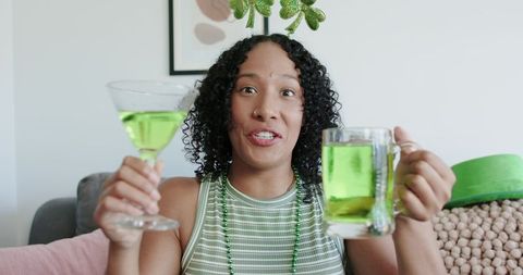 African american woman celebrating st patrick's day with green cocktail and beer