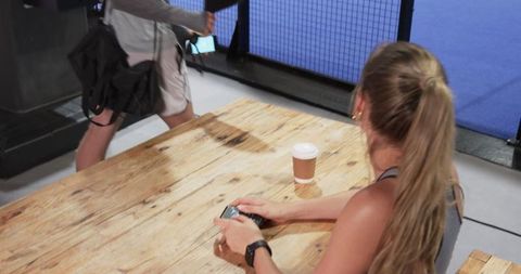 Woman relaxing after workout holding smartphone in sports facility
