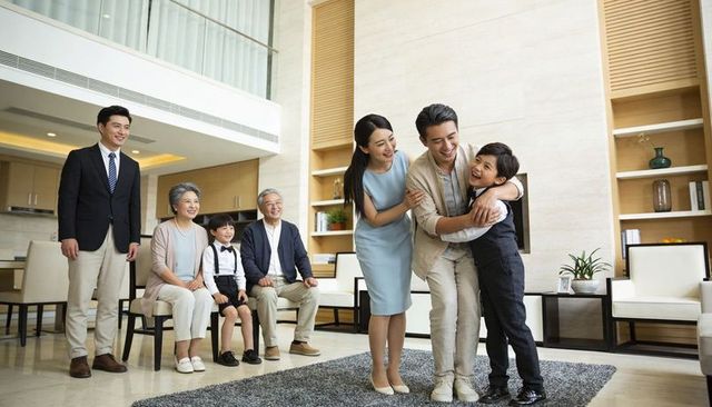 Multigenerational family celebrating at home with father hugging son in modern living room