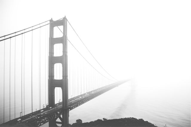 Golden Gate Bridge extending into dense fog, creating a mystic and dreamy atmosphere. Ideal for use in travel magazines, blogs about San Francisco or iconic landmarks. Suitable for illustrating concepts of journey, mystery, or nature's effects on human structures.
