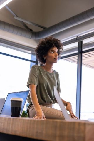 Woman contemplating in modern office environment with laptop