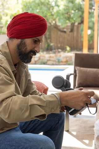 Man Relaxing Outdoors Using Percussion Massager by Poolside