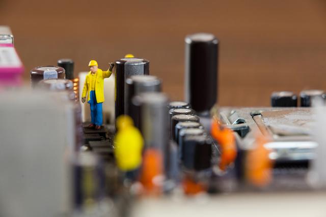 Conceptual image of miniature workers working on chip of motherboard